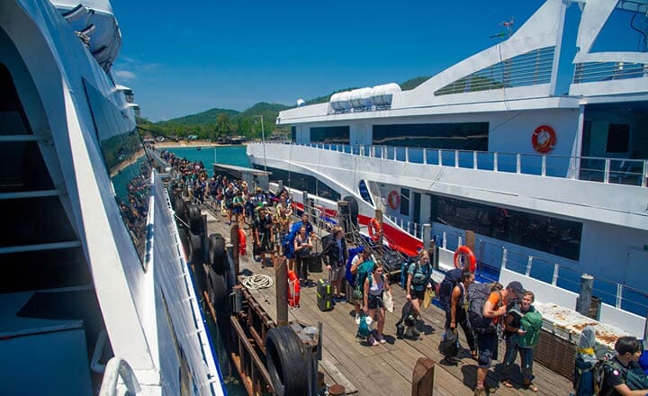 Hurried tourists with luggage on Tung Makham Ferry Pier, Chumphon, boarding Lomprayah Ferries to Koh Tao and Koh Samui, capturing the excitement of traveling to Thailand's exotic islands.